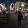 Pedestrians walk along Fifth Avenue in the Gaslamp District of downtown San Diego at night.